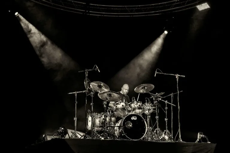 Dynamic concert scene with a drummer rocking on stage under spotlights in San Salvador.