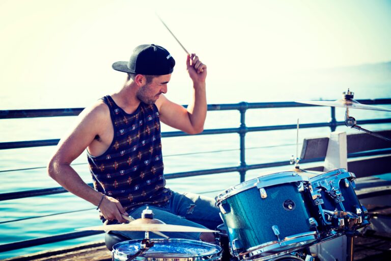 Energetic street drummer performs on Santa Monica Pier with a vibrant ocean backdrop.